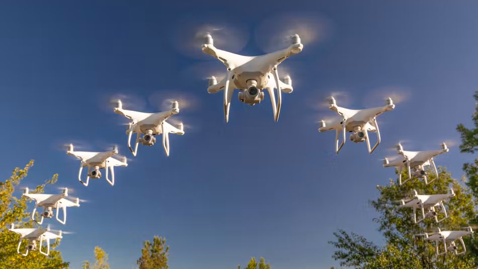 A group of white quadcopter drones flying in formation against a blue sky.